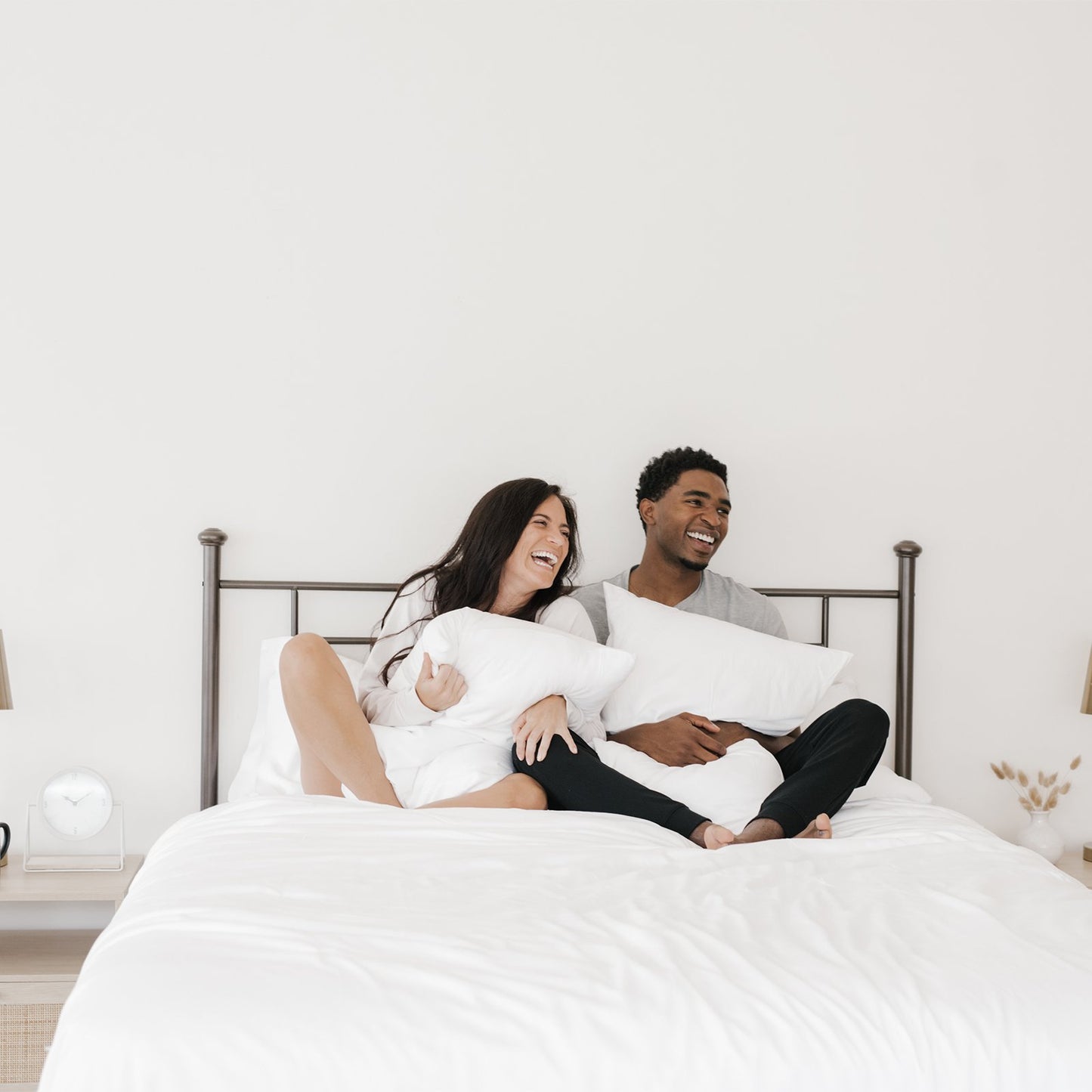 couple smile while holding silk pillows