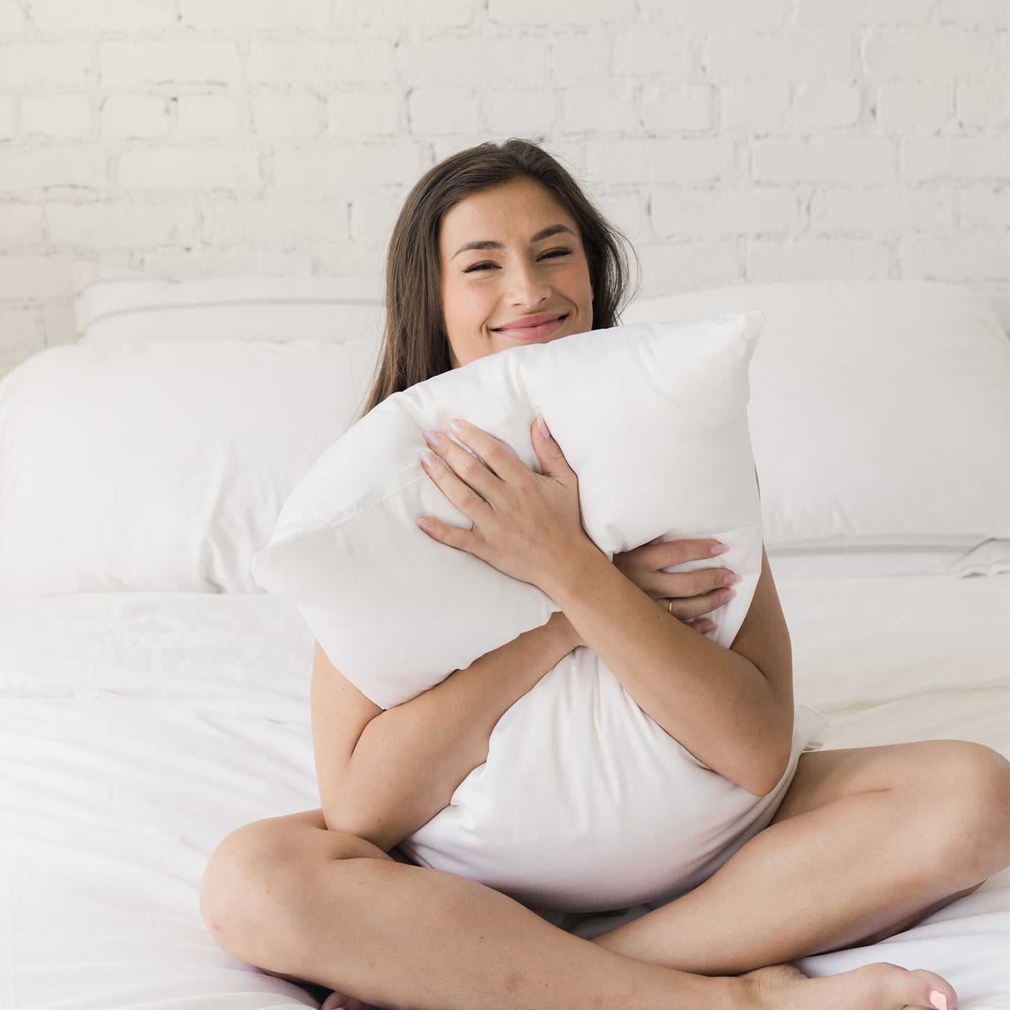 smiling woman hugging silk pillows